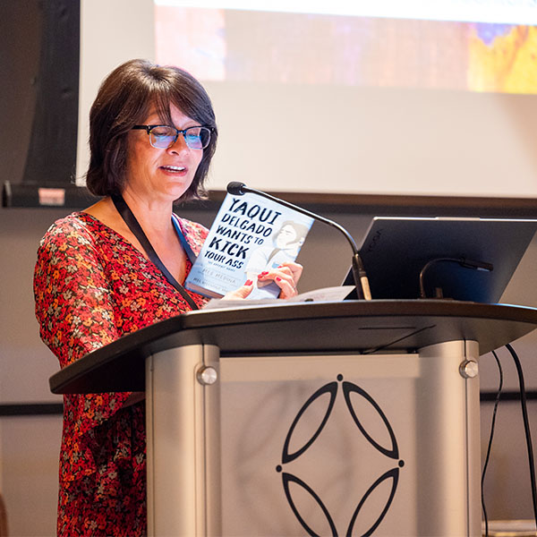 Author Meg Medina at 2024 TLA Annual Conference Opening Awards and Author Luncheon reading at a podium