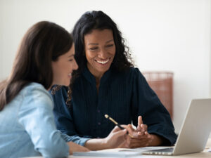 Two women sitting at a laptop discussing