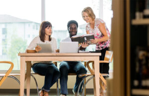 A man and a woman seated at a table being helped by a librarian