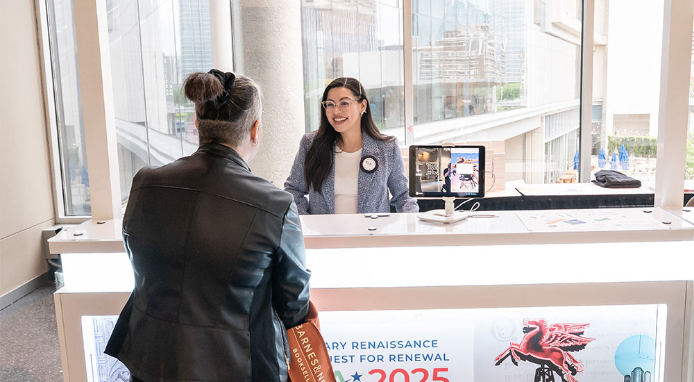 A TLA volunteer helping a conference attendee at a help desk.